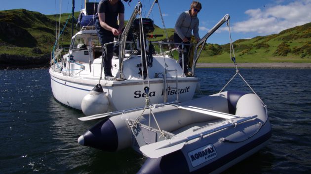 A dinghy being raised by davits at the back of a yacht