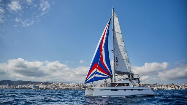 A catamaran sailing with a red, blue and white sail