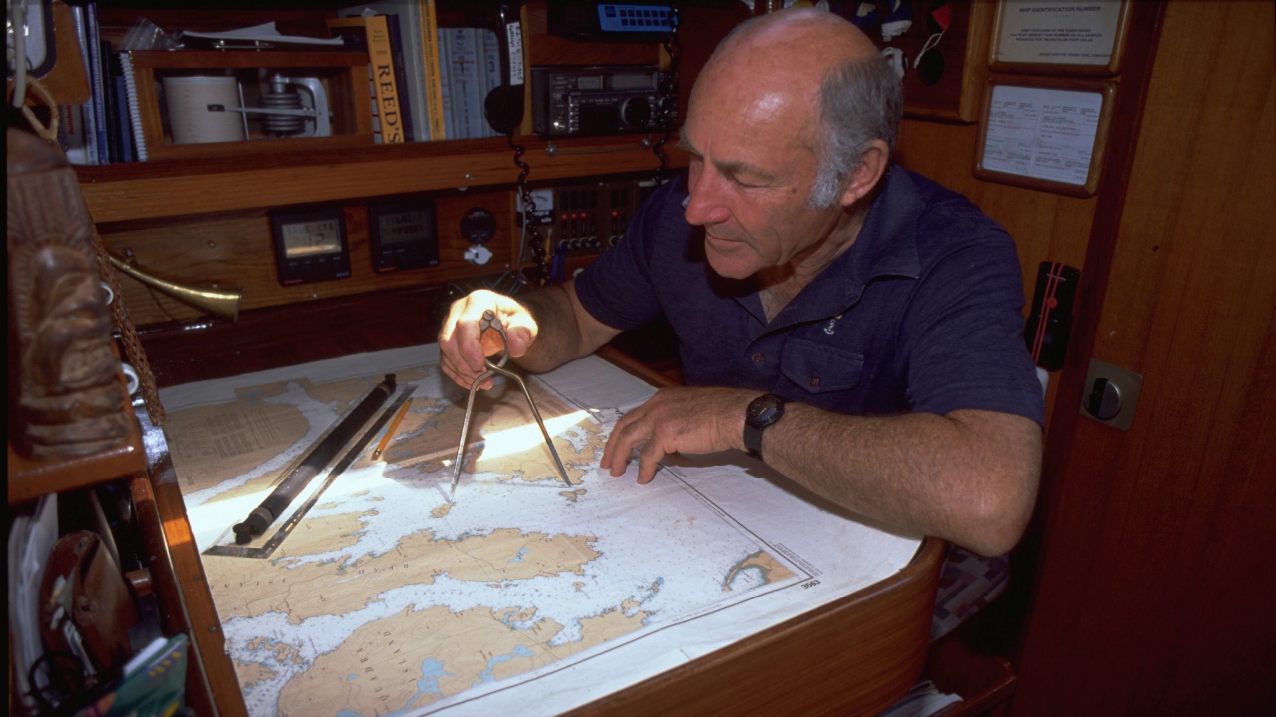 A man using paper charts to navigate on a boat