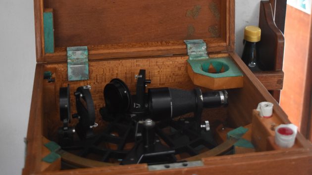 A black sextant in a wooden box
