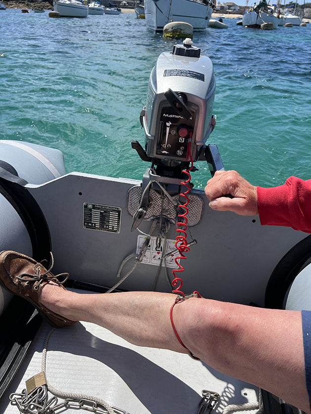 A kill cord from an outboard engine around the leg of a sailor